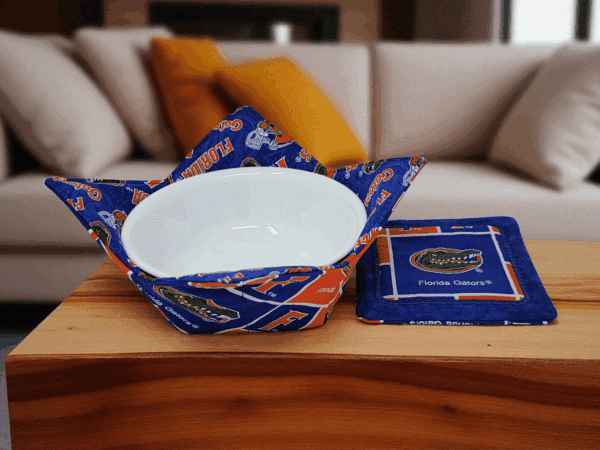 Handmade bowl cozy and matching coaster in Florida Gators fabric displayed on coffee table